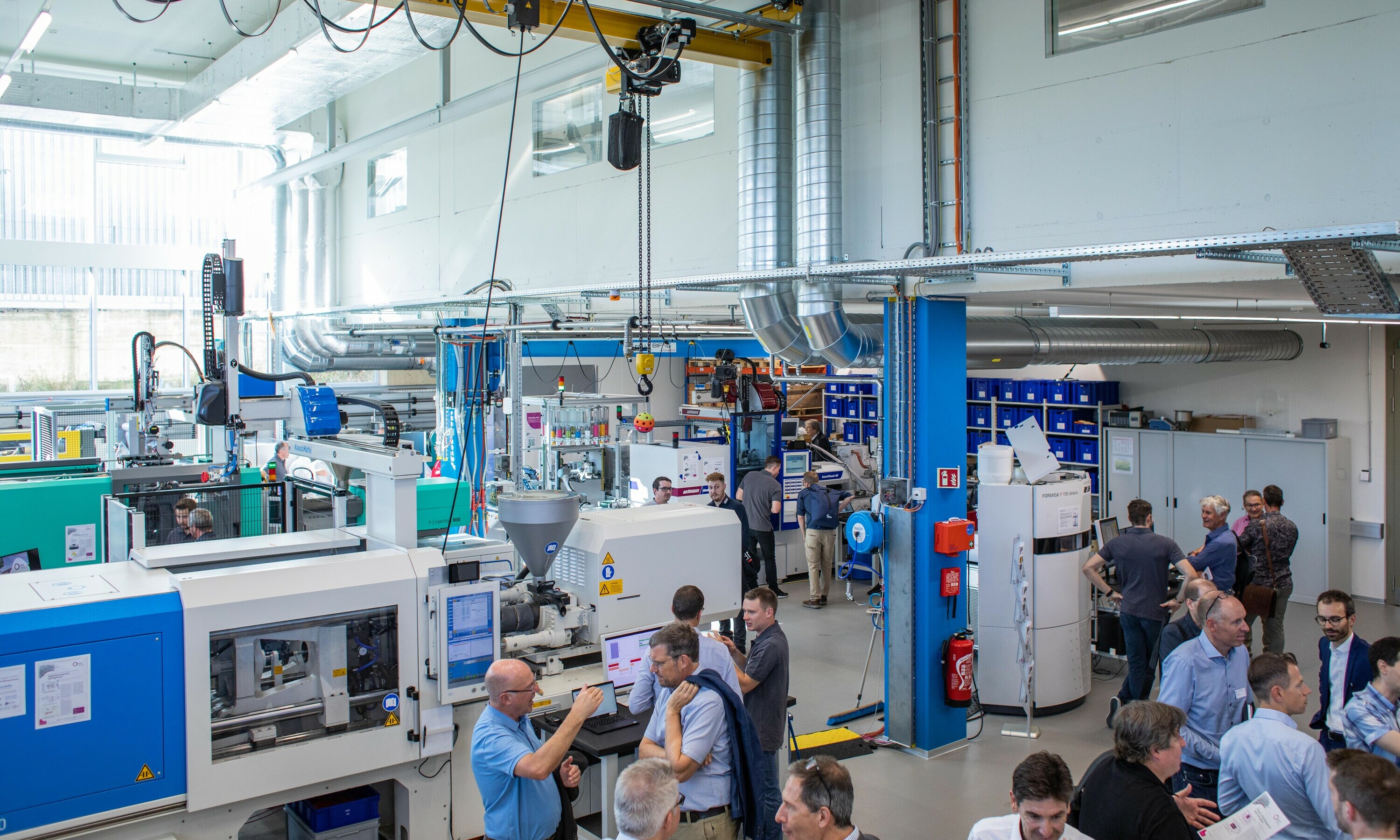Personen stehen in Maschinenhalle im Techpark vom IWK anlässlich des Rapperswiler Kunststoff-Forums
