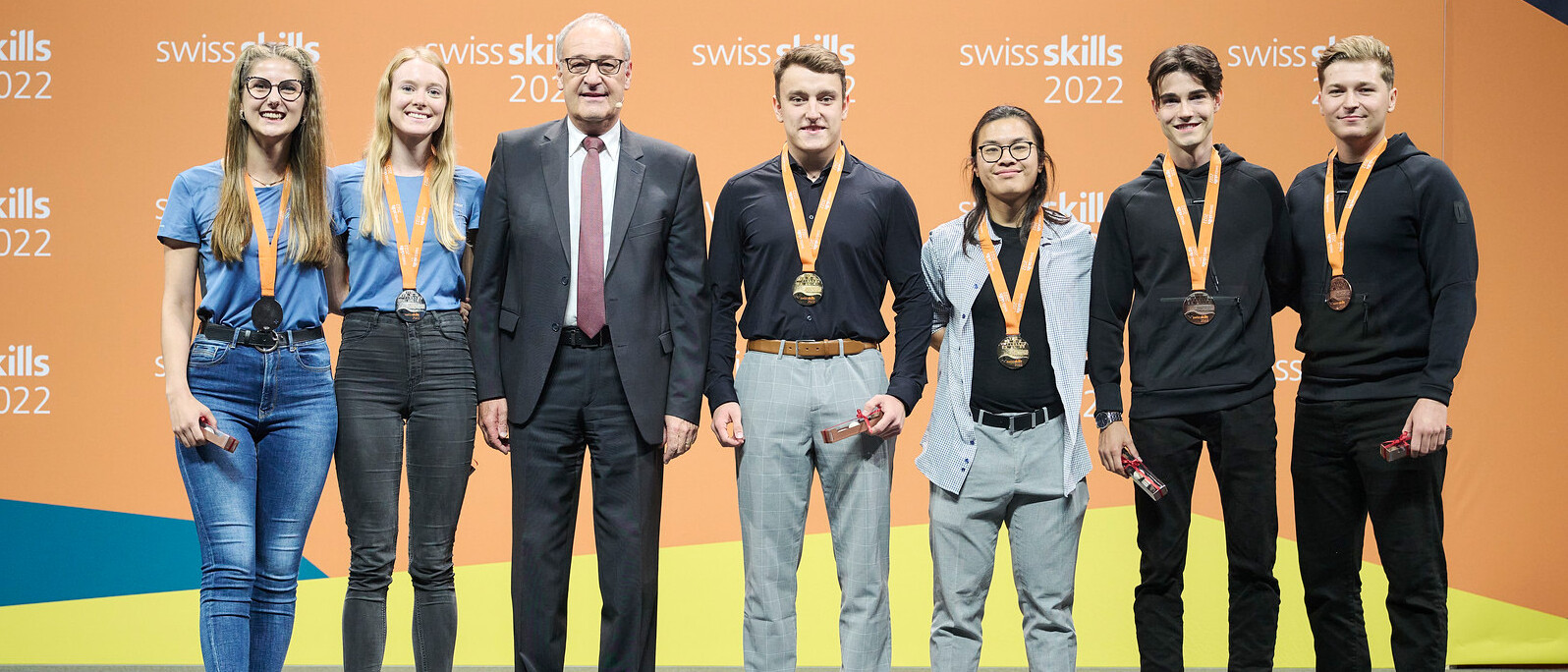 Maria Näf und Julia Koch neben Bundesrat Guy Permelin sowie den Erst- und Drittplatzierten der SwissSkills 2022 in der Disziplin «Entrepreneurship»