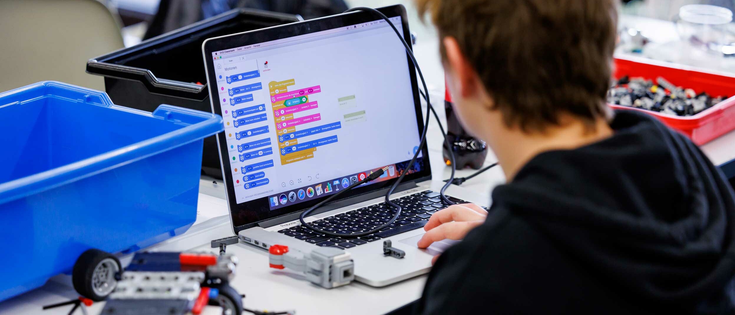 Jugendlicher passt die Software seines Roboters an. 
