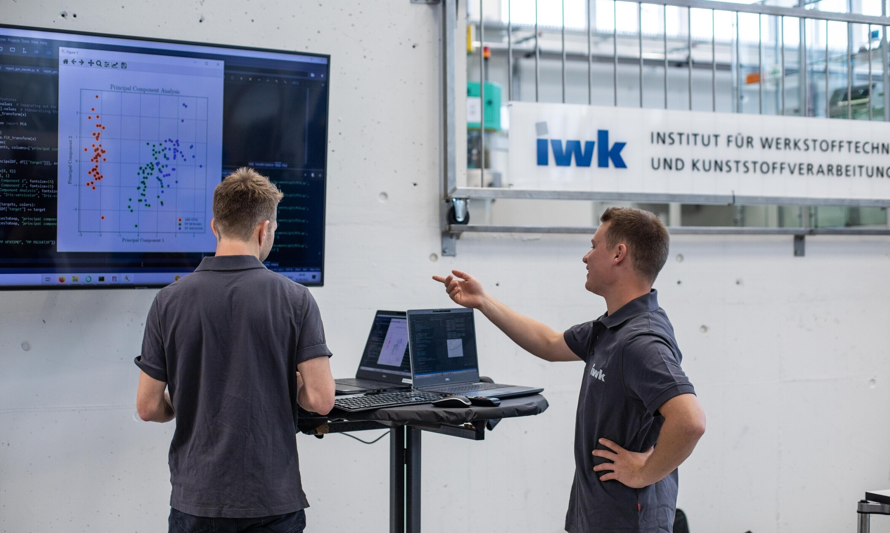 Mitarbeitende im Techpark am IWK stehen in Maschinenhalle und diskutieren über ein Projekt