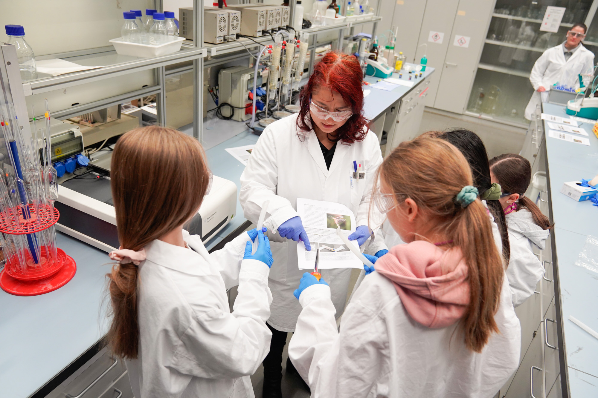 Eine Mitarbeiterin der OST Ostschweizer Fachhochschule führt mit Schülerinnen ein spannendes Experiment im Chemielabor durch.