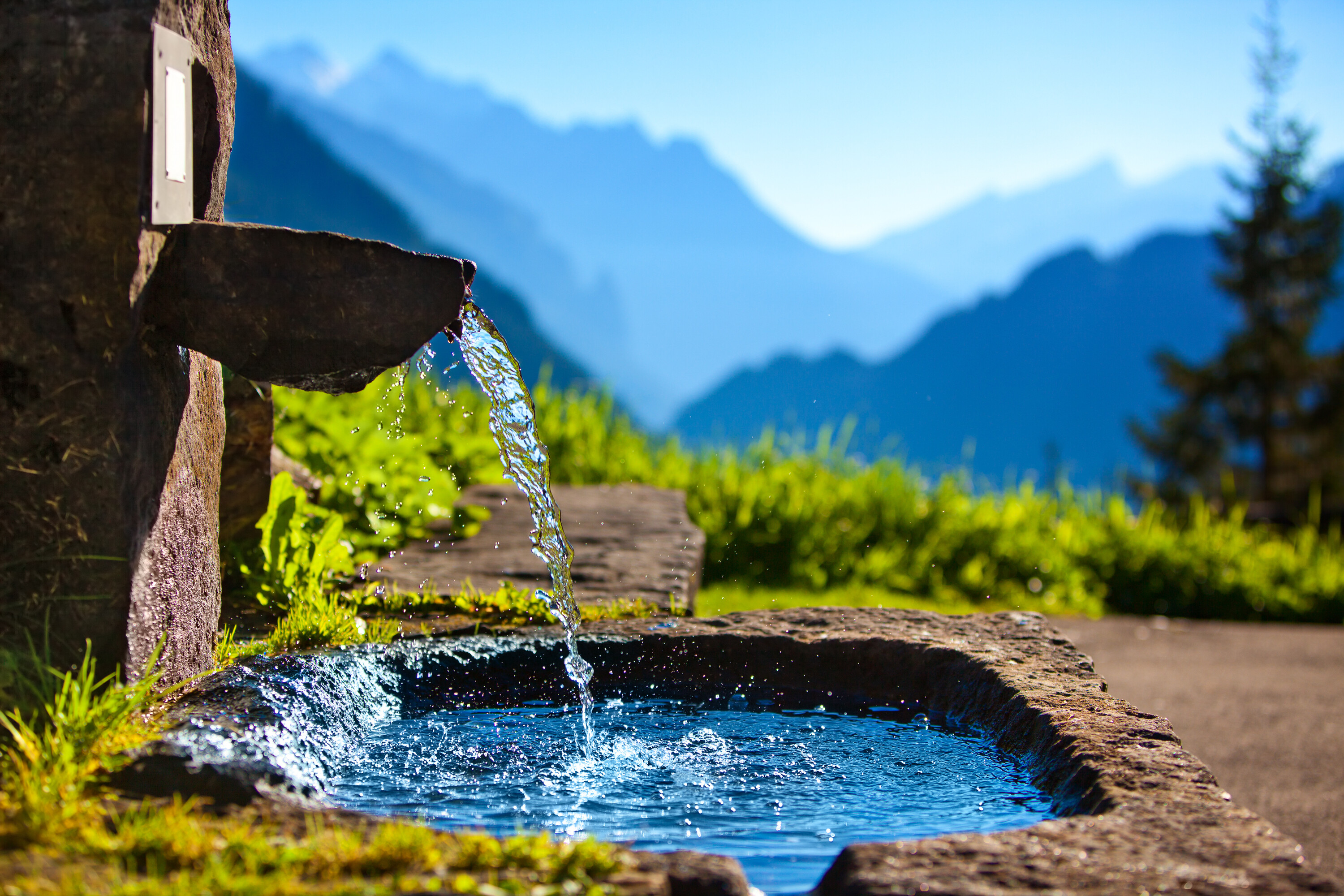 Bild eines Brunnens vor Bergkulisse