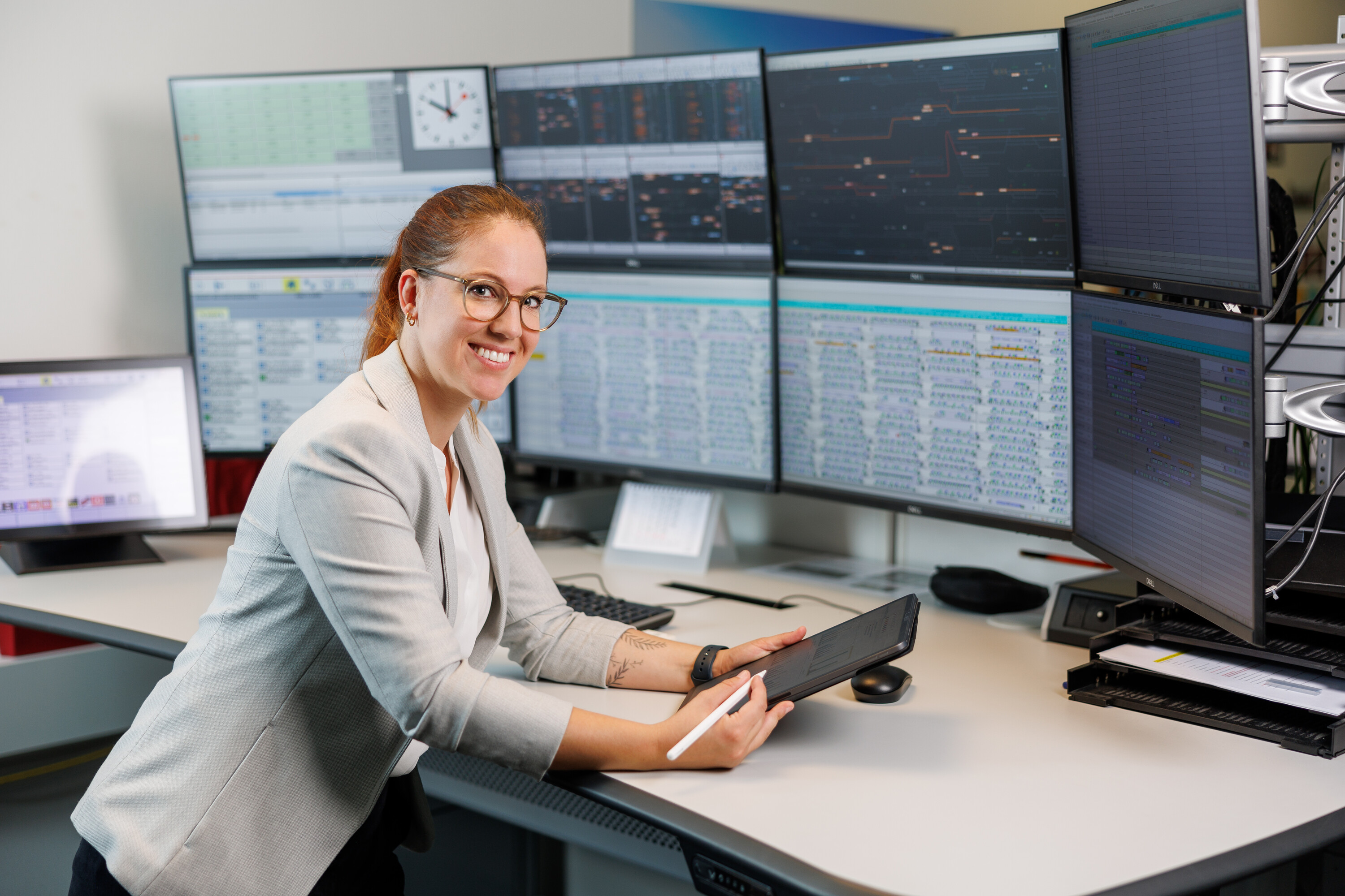 Eine junge Frau vor einer Wand aus 8 Monitoren schaut in die Kamera (Symbolbild für Master Data Science MSE)
