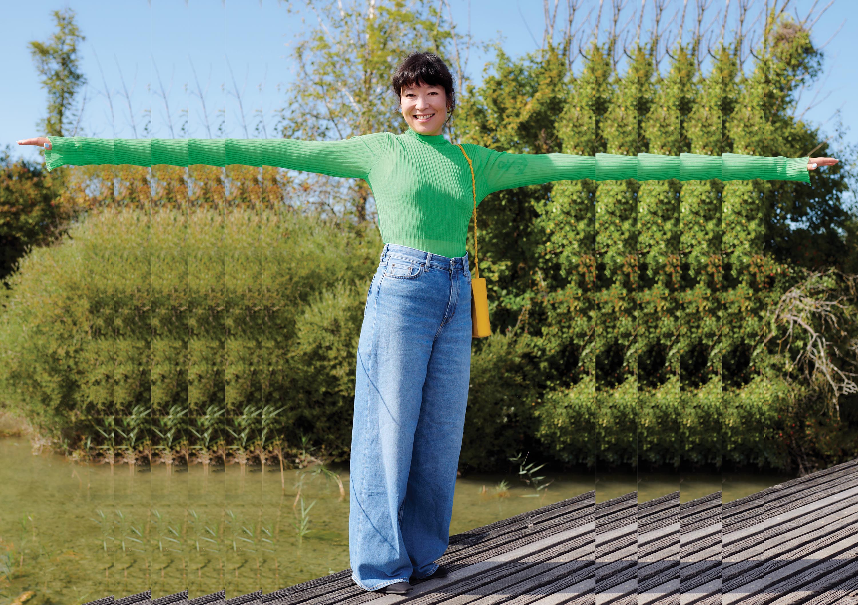 Eine Frau streckt die Arme aus. Im Hintergrund Natur. 