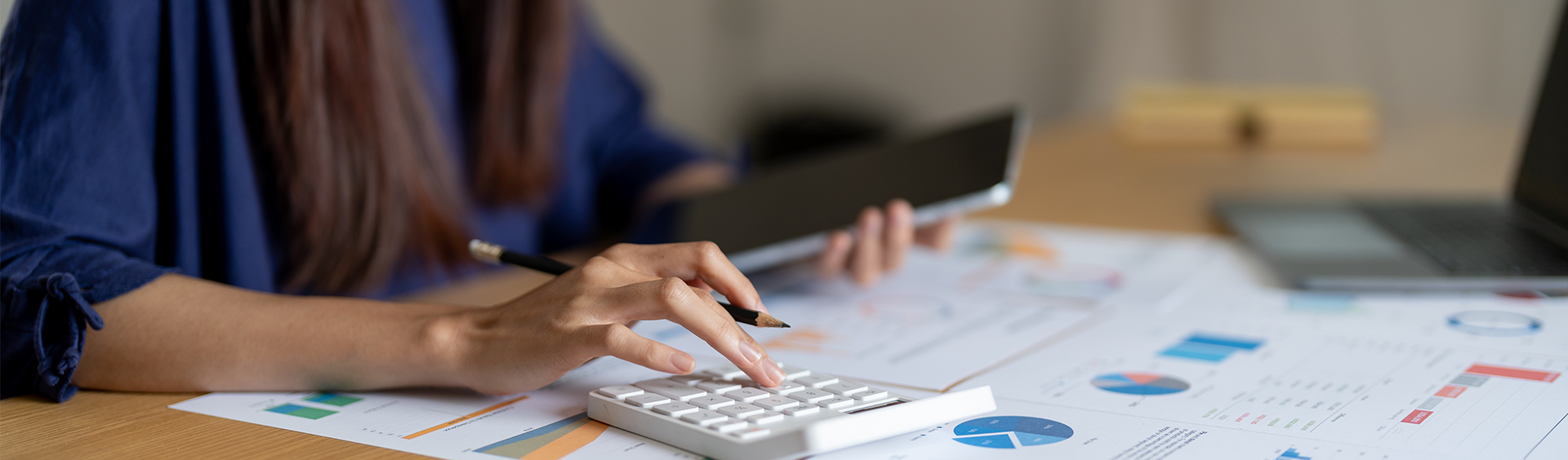 Person analysiert Finanzdokumente mit Tablet und Taschenrechner – Fokus auf Accounting und Corporate Finance.